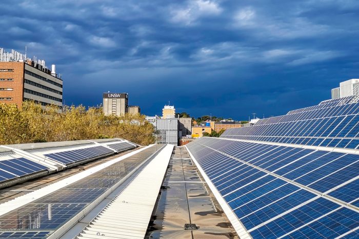 Rooftop solar panels in the foreground with UNSW Library in the background against blue sky