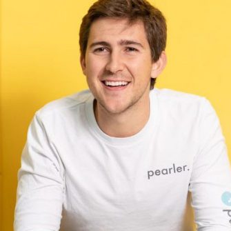 Kurt Walkom smiles in a pearler shirt against a yellow background