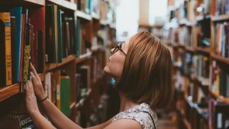 Woman looking at books on a library shelf