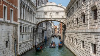 People touring in gondolas under the famous baroque style Bridge of Sighs at Venice city, Italy.