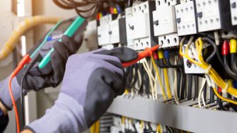 Picture of electrical engineer testing installations and wires on relay protection system.