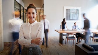 Portrait of young white woman in a busy modern workplace