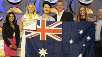 Show Ethan at 2022 Microsoft Office Specialist (MOS) World Championship in Disney Land, California holding Australian flag on stage