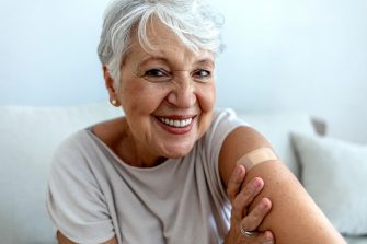 Proud mature woman smiles after vaccination with bandaid on arm