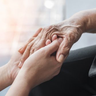 a younger person's hand gently hold an older person's hand