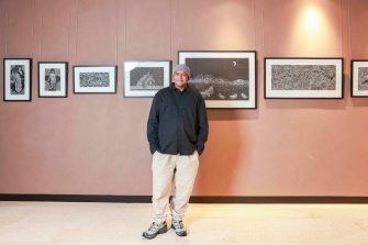 Warren Foster (Senior) (Yuin-Djirringanj), with prints by artist Aaron Kennedy. Photo by Katherine Griffiths.