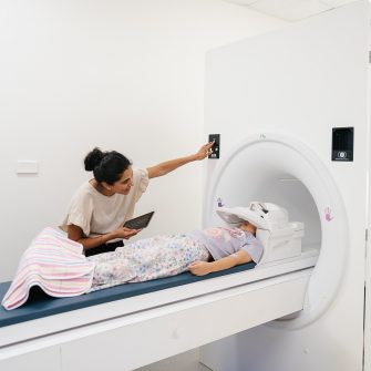 Doctor and patient using an mri simulator in Sydney Children's Hospital. Child is relaxed on the tray and about to enter the machine.
