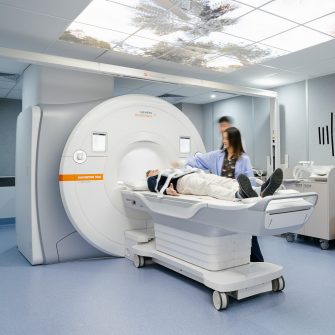 Patient laying on the tray of a large mri scanner in RINSW