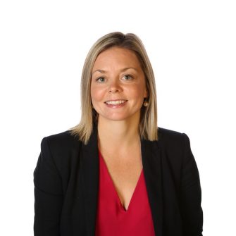 Portrait of a blonde woman in a black blazer with a red top