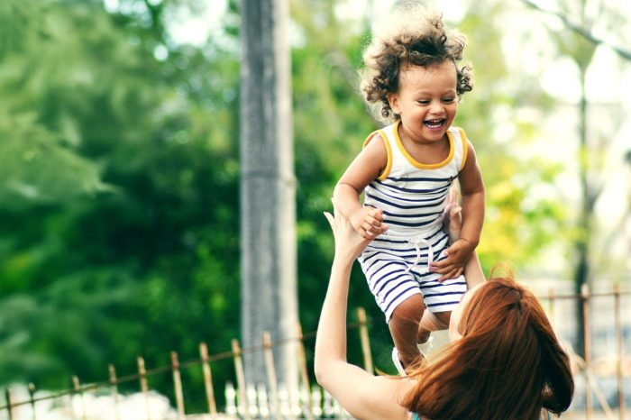 Woman throwing a young girl up in the air in a playful manner