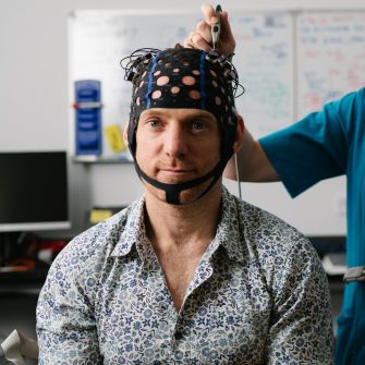 Portait of a DVCRE staff member AJ Epstein wearing a mesh hat with sensors on it