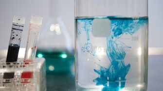 a beaker fill with colouring dispersing in clear liquid inside