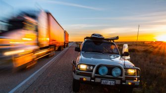 Grey 4WD on the side of a road with a truck driving past