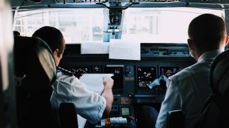 Two pilots in an aeroplane cockpit seen from behind