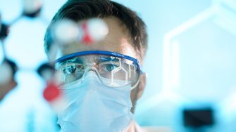 A scientist working with a mask and protective glasses