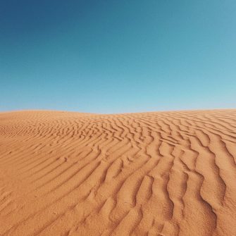 Red sand dunes under a clear blue sky