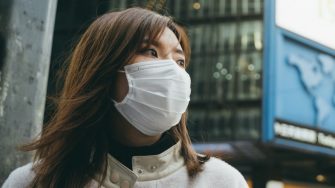 Young woman wearing a protective face mask to prevent the spread of germs and viruses in the city