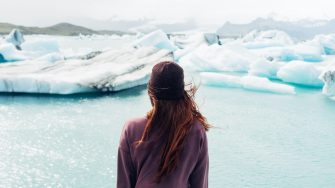 Woman wearing purple shirt overlooking a body of water and snow covered field