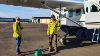 Photo of Prof Richard Kingsford and Mr Paul Wainwright wearing bright yellow fire retardant safety jackets, standing next to a light aircraft.