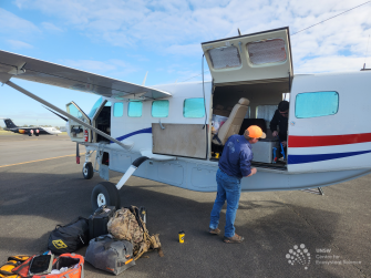 Small plane with a person loading equipment into the  back