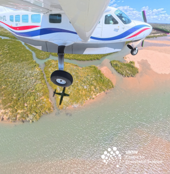 Light airplane in flight over water and headland
