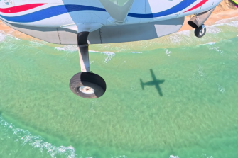 Light airplane in flight over water and headland behind