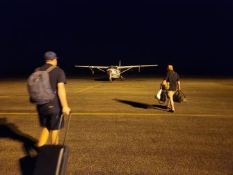 Two people walking towards a light airplane from behind