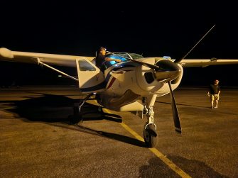 Person standing at door of light aircraft in morning dark