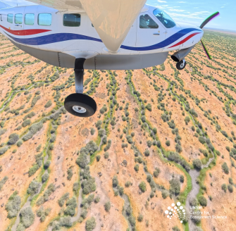 Light airplane in flight over water channels with red earth and trees
