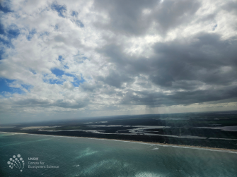 Aerial view of ocean in foreground with ocean channels with mountains and sky in the distance