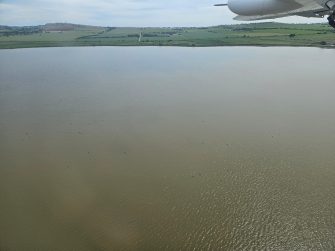 Aerial view of vast waterbody with land and sky in the distance