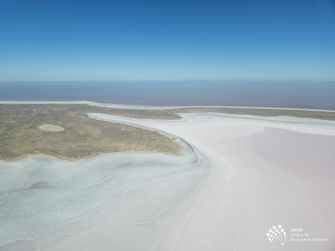 Aerial view of white area at front and right, land to left and sky on horizon