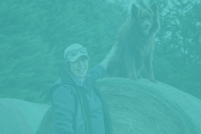 Samantha Wan smiling next to a dog sitting on a hay bale with a blue overlay over the image