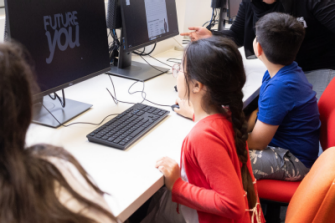 Primary-aged students working at computers which have Future You resources on the screens. 