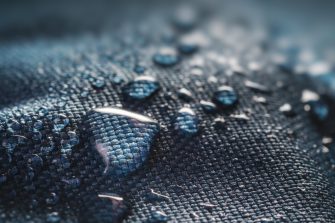 Water droplets sitting on top of a water resistant material. Materials such as rain coats can contain PFAS chemicals.