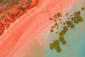 Roebuck bay in broome, western australia as seen from the air. SHowing the pink beach, red cliffs, turquoise water and green mangroves. 
