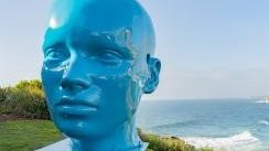 A blue head sculpture set overlooking the sea