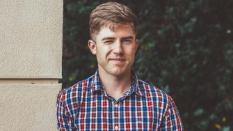 Man standing beside wall winking