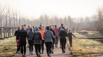 People running along a concrete path past leafless trees