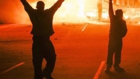 Protestors parade in the parking lot of a burning auto parts store in Ferguson, Mo. on Nov. 24, 2014