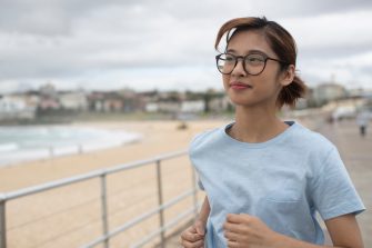 Female student running on boardwalk in Bondi beach