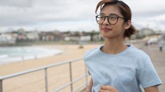 Female student running on boardwalk in Bondi beach
