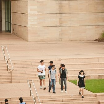 Zoomed out view of students walking down Scientia Steps and UNSW logo in the background