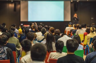 Rear view of Asian audience joining and listening speaker talking on the stage in the seminar meeting room or conference hall, education and workshop, associate and startup business concept