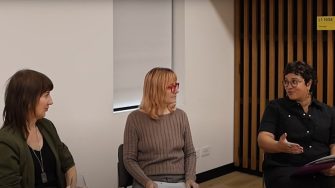 three women are seated, in conversation