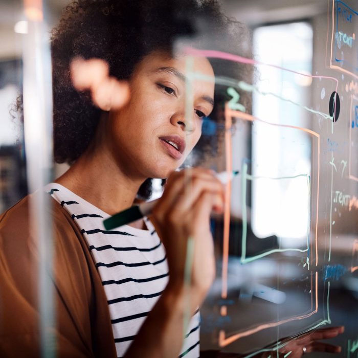 Woman working and writing on the glass board in office