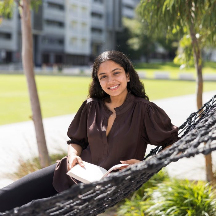 Rifah Tamana sitting in a hammock, reading a book