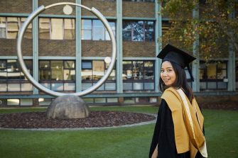 A graduate in gown on UNSW Library Lawn