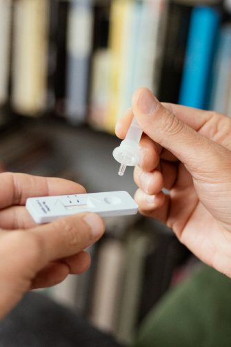 Picture of someone's hands placing their own sample into the covid-19 antigen diagnostic test device