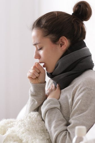 Young woman in bed coughing
